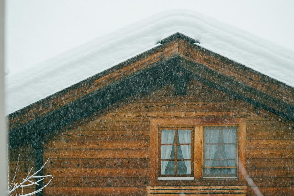 Wooden house with snow on the roof in a snow storm.